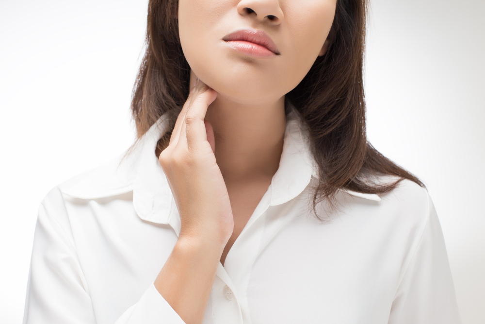 A woman in a white shirt is holding her neck.