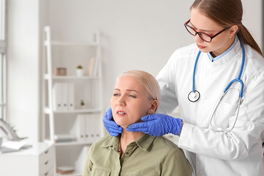 A doctor is examining the neck of a patient in a hospital.