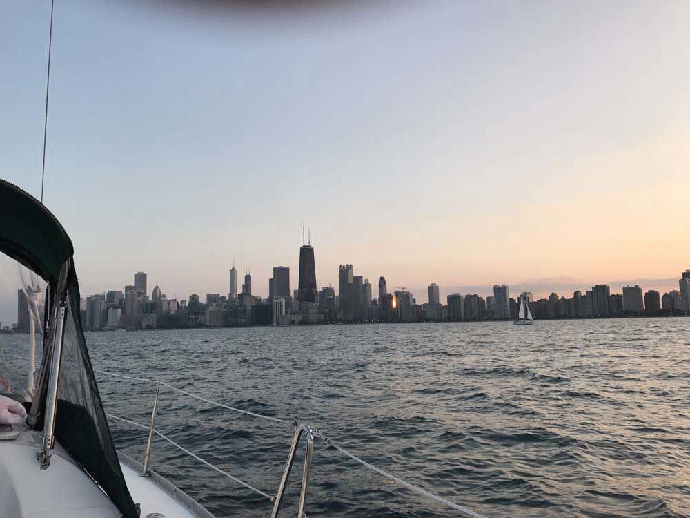 A boat is floating on top of a body of water with a city skyline in the background.