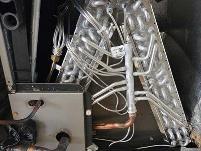 Metal piping and wiring inside an industrial machine, with shiny silver tubes and a copper pipe visible