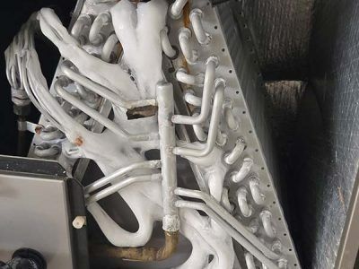 A white mechanical sculpture with many tubes and metal rods on a dark background