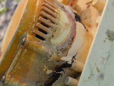 Close-up of a rusty yellow industrial motor with corrosion and grime