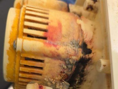 Close-up of a burnt, melted plastic device with black scorch marks and yellow-orange discoloration.