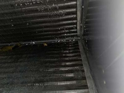 Dark corrugated metal surface with a corner seam and bright light glare on the right