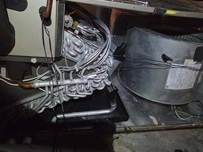 Close-up of tangled silver wires and a gray motor or pump inside a machine compartment.