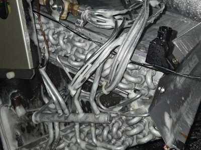 A chaotic pile of tangled silver metal pipes and hoses inside a machinery compartment.