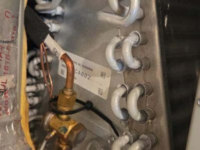 Close-up of copper piping and white insulated tubing inside a metal HVAC unit