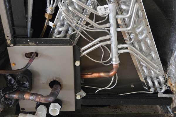 Close-up of HVAC unit piping and copper refrigerant lines inside a metal equipment panel