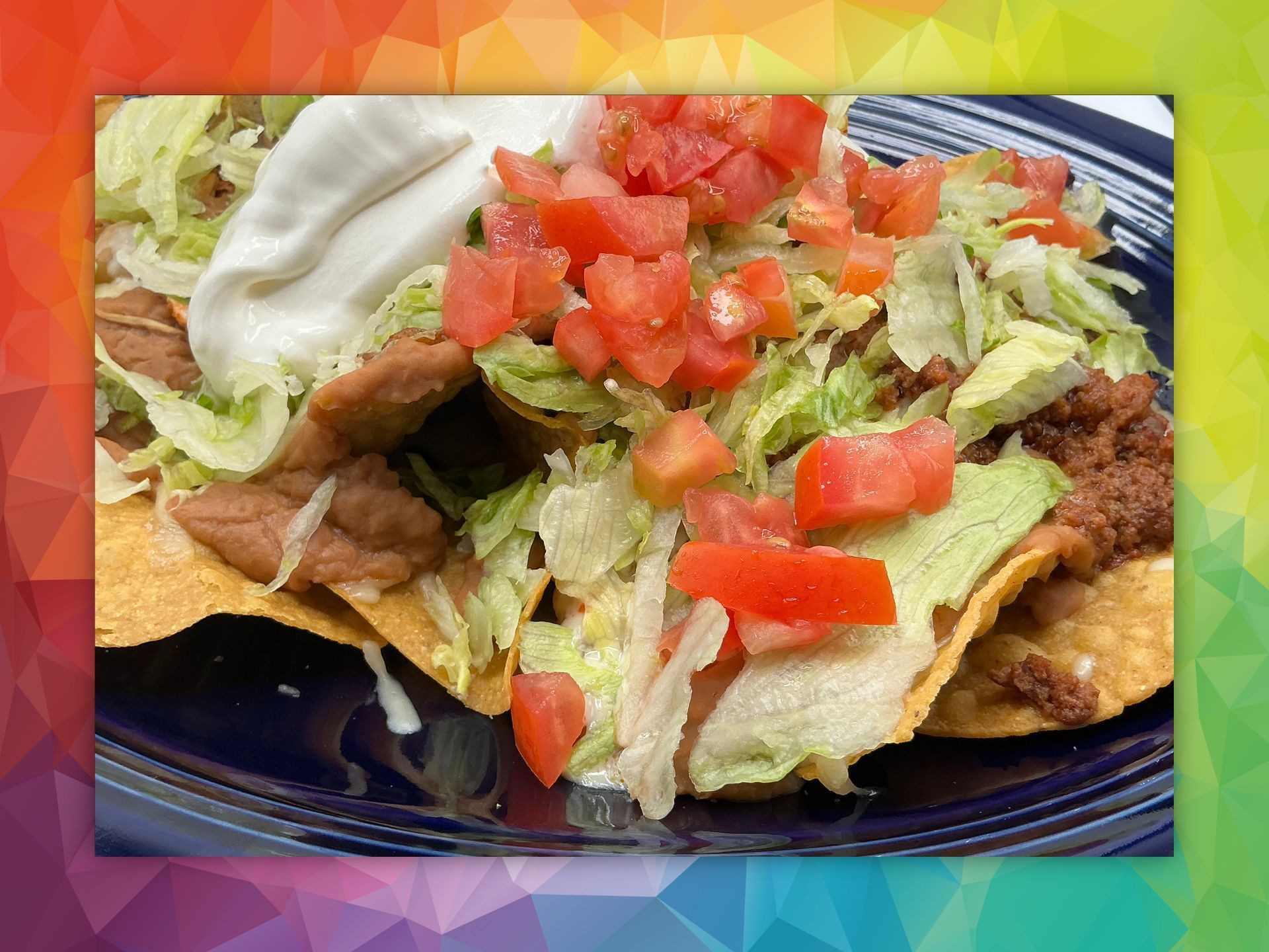 Nachos with refried beans, lettuce, tomatoes, and sour cream.