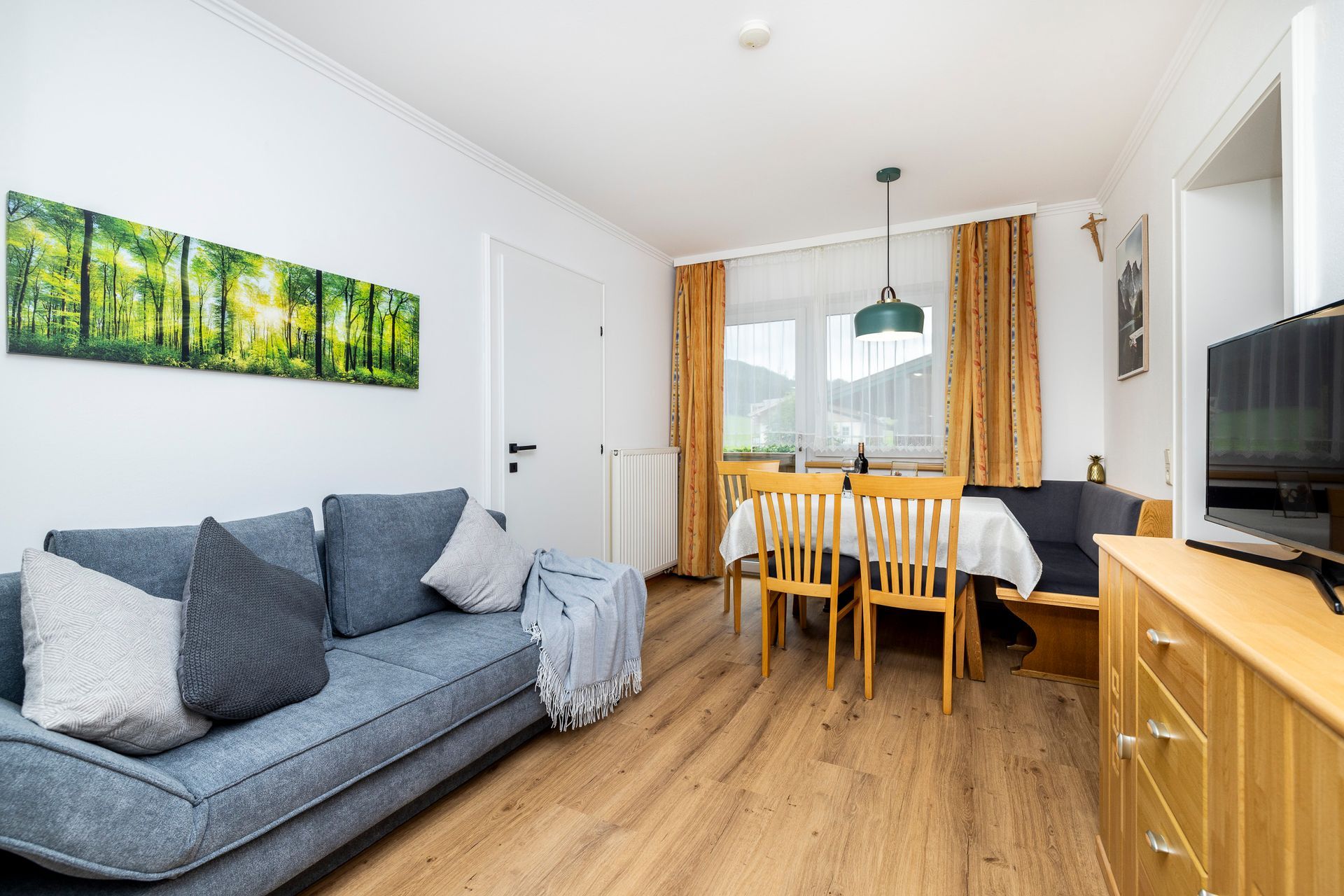 Ein Wohnzimmer mit Couch, Tisch, Stühlen und Fernseher.