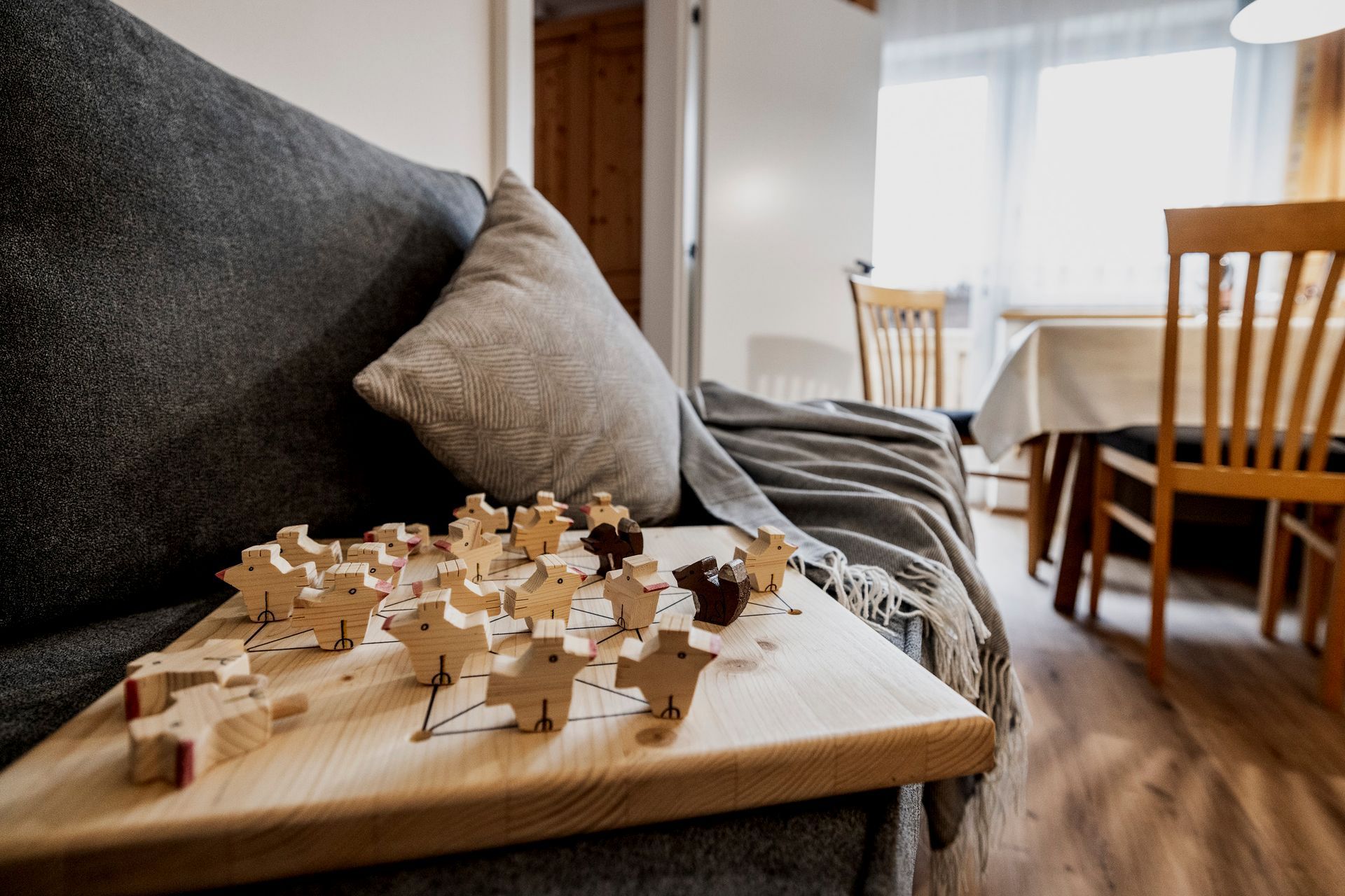 Ein Holzpuzzle liegt auf einem Holztisch neben einem Sofa in einem Wohnzimmer.