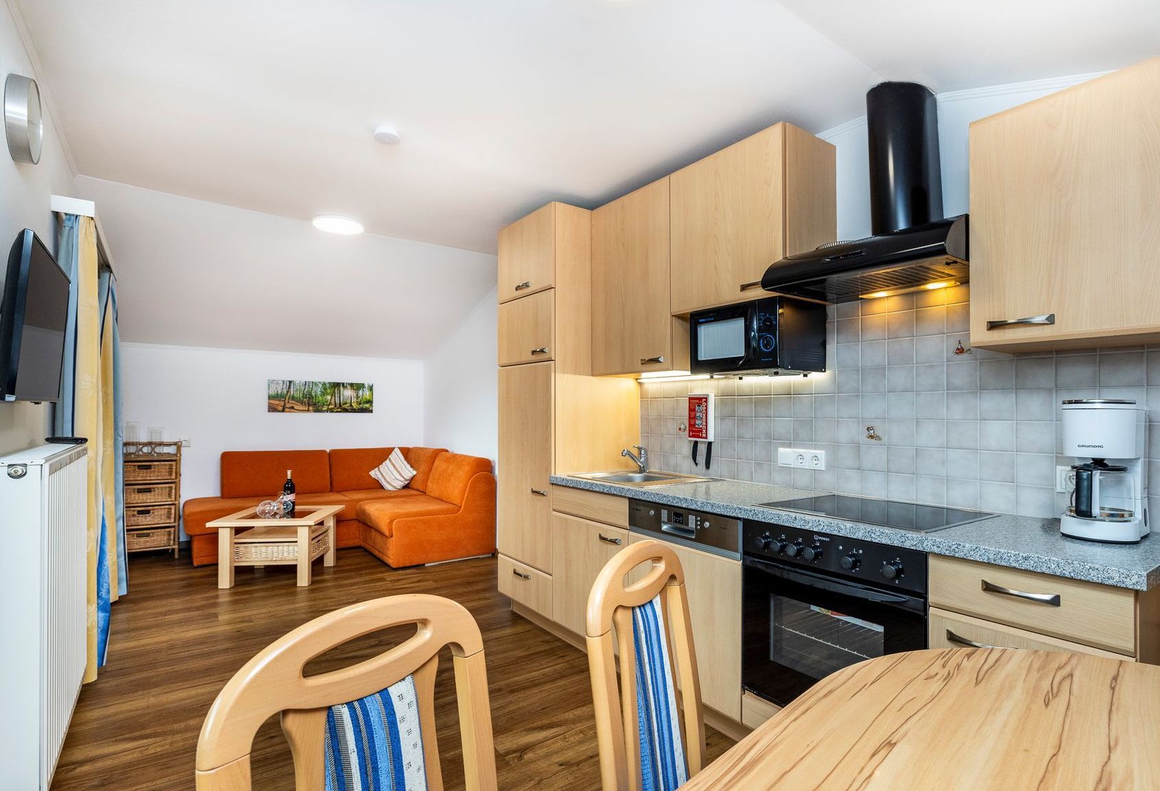 Eine Küche mit Tisch und Stühlen und einer Couch im Hintergrund.