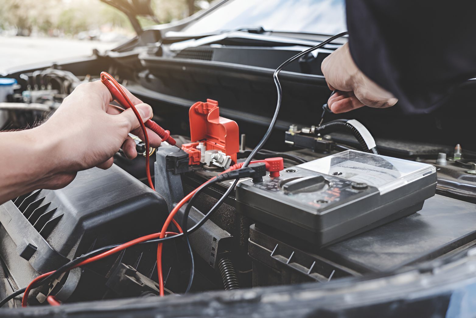 A Person is Working on a Car Battery With a Multimeter — K & T Ballina Mechanical In Ballina, NSW