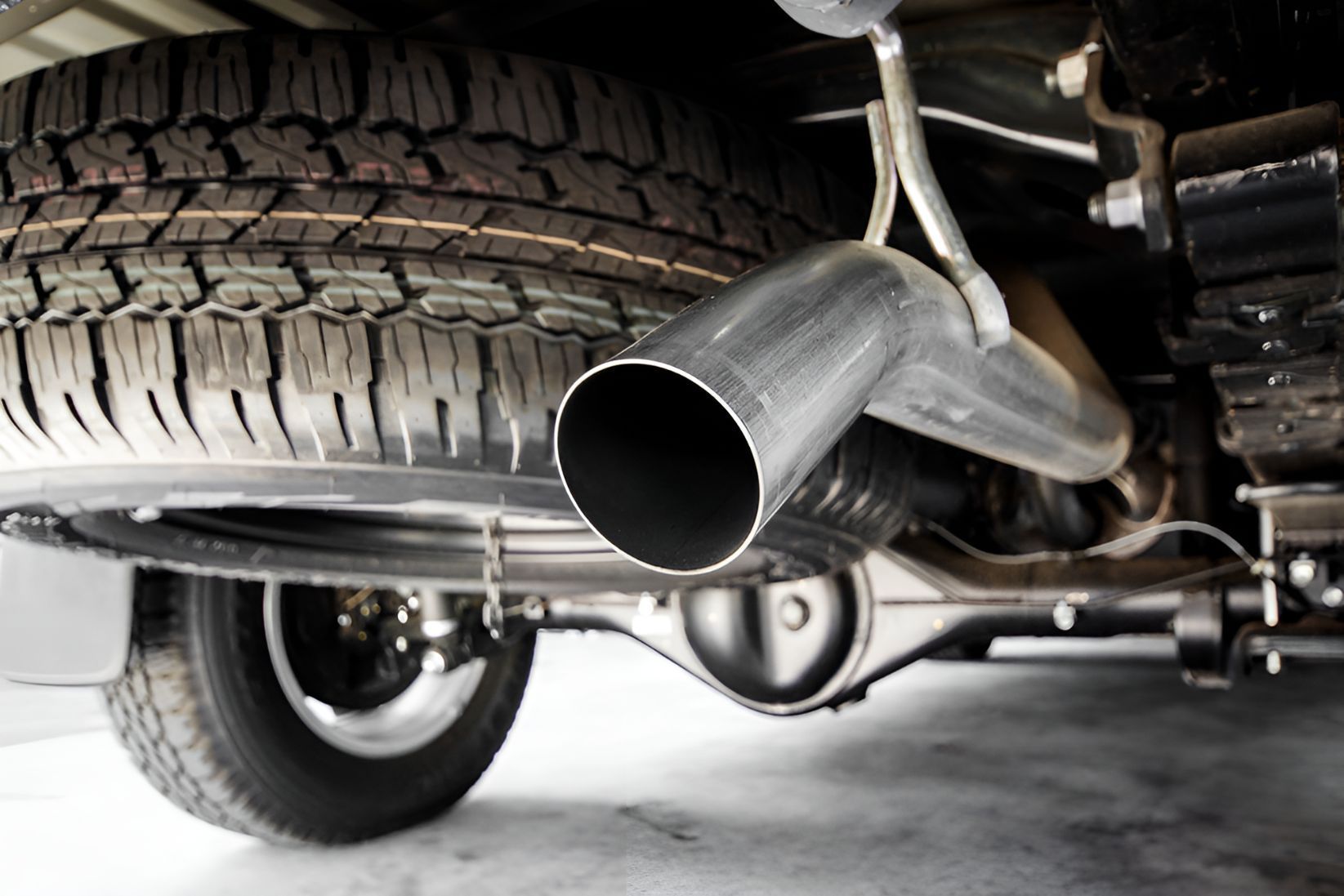 A Close Up of a Car Exhaust Pipe With a Tire in the Background — K & T Ballina Mechanical In Ballina, NSW