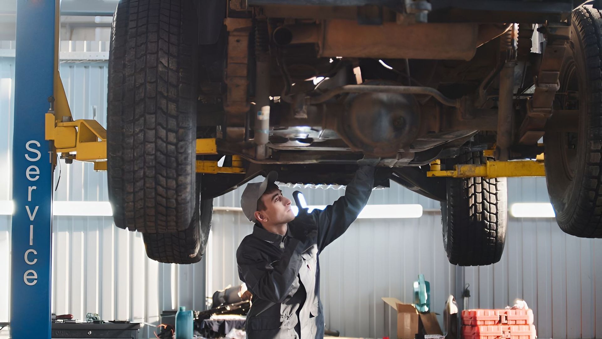 A Man is Working Underneath a Truck on a Lift in a Garage — K & T Ballina Mechanical In Ballina, NSW