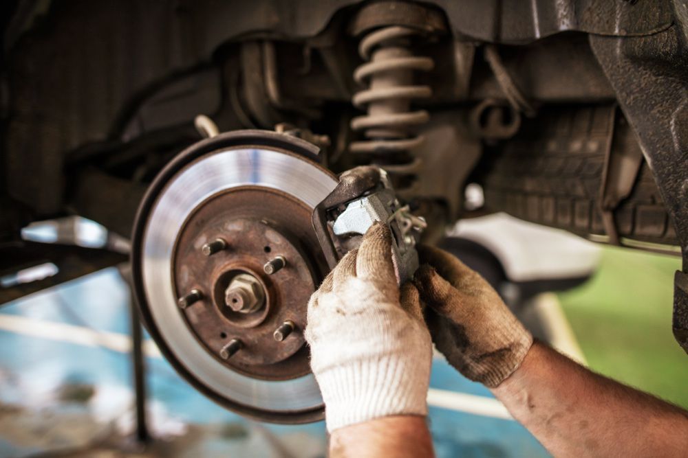 A Person is Working on the Brake Pads of a Car — K & T Ballina Mechanical In Ballina, NSW