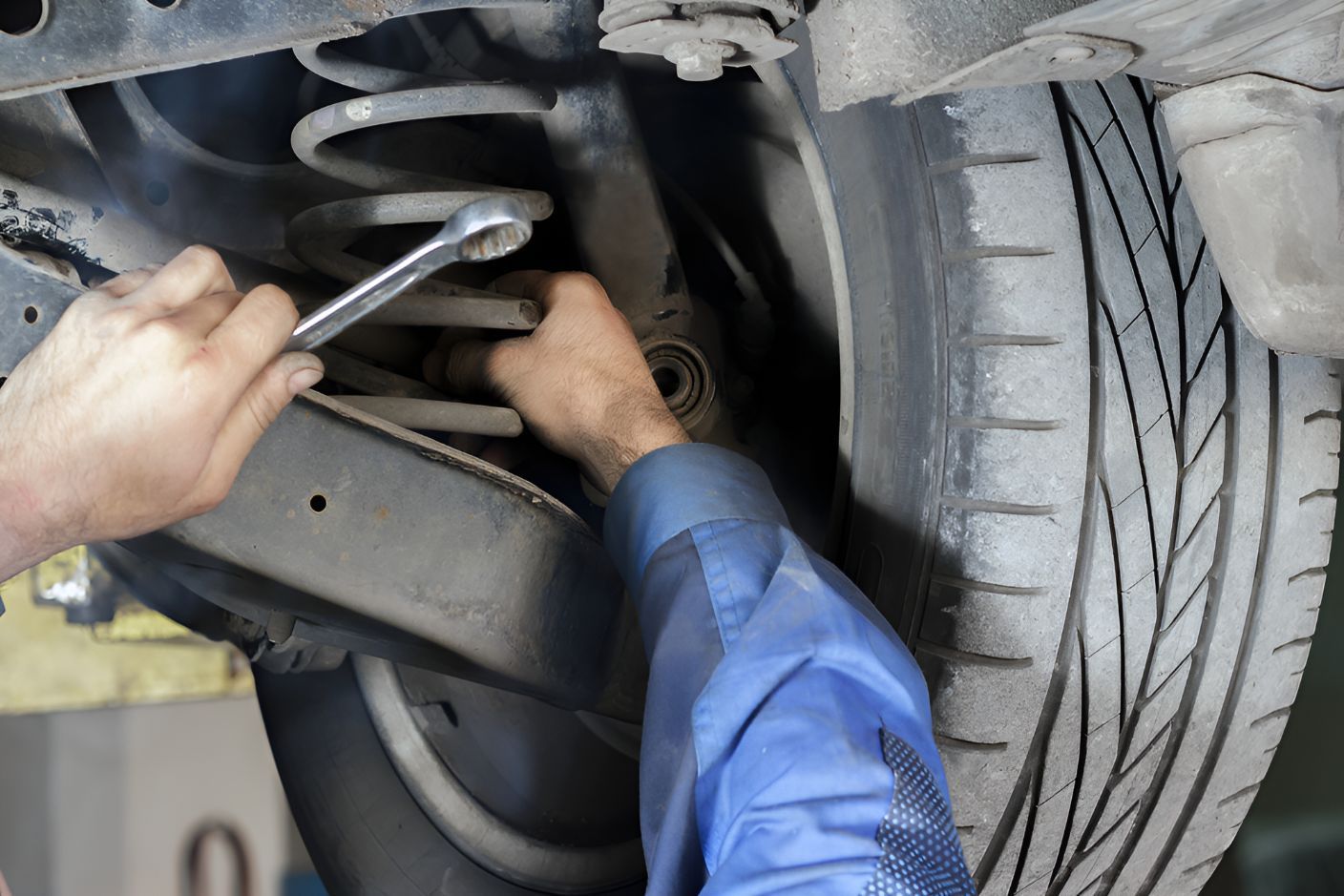 A Man is Working on the Suspension of a Car With a Wrench — K & T Ballina Mechanical In Ballina, NSW