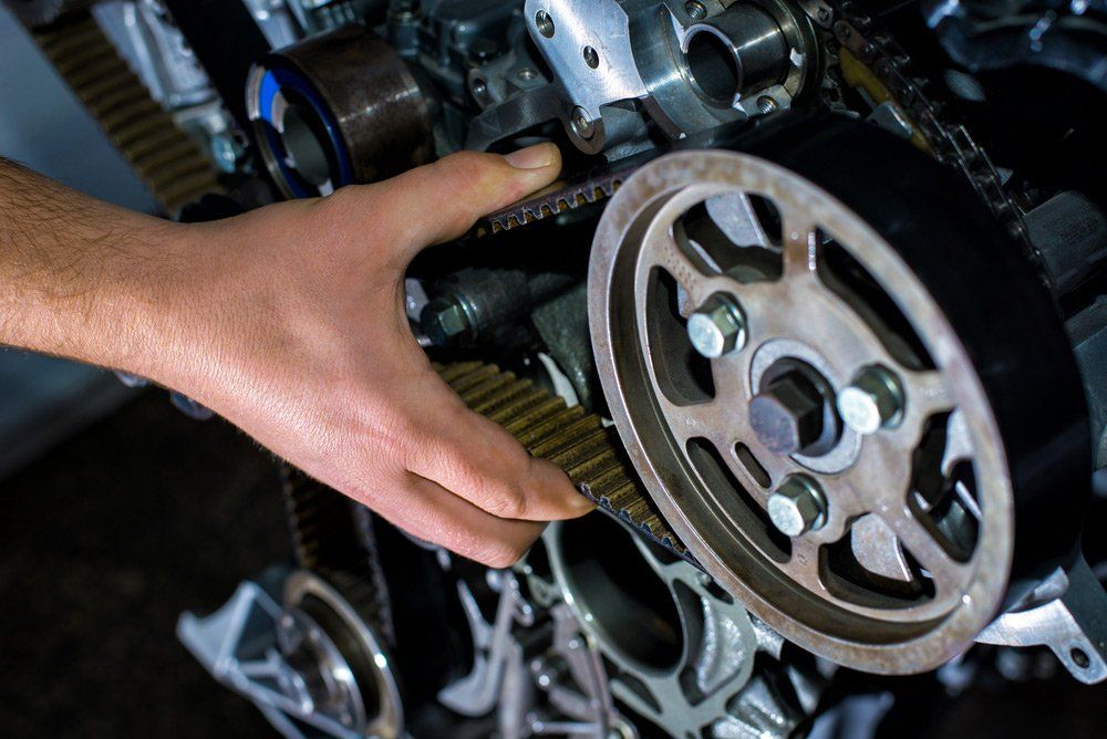 A Person is Fixing a Belt on a Car Engine — K & T Ballina Mechanical In Ballina, NSW