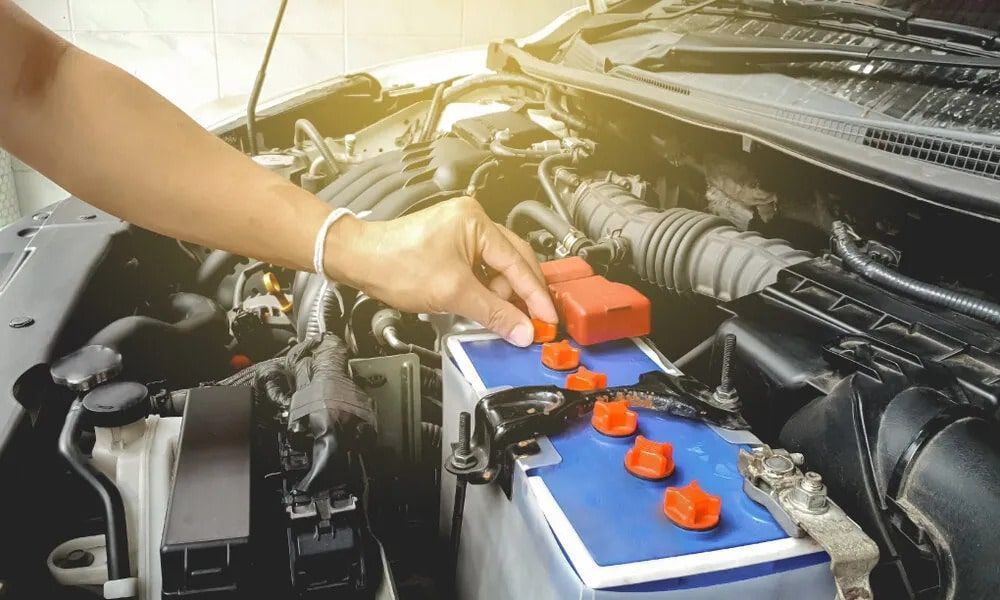 A Person is Plugging a Battery Into a Car — K & T Ballina Mechanical In Ballina, NSW