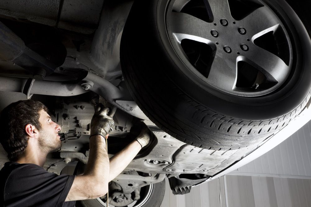 A Man is Working Under a Car in a Garage — K & T Ballina Mechanical In Ballina, NSW