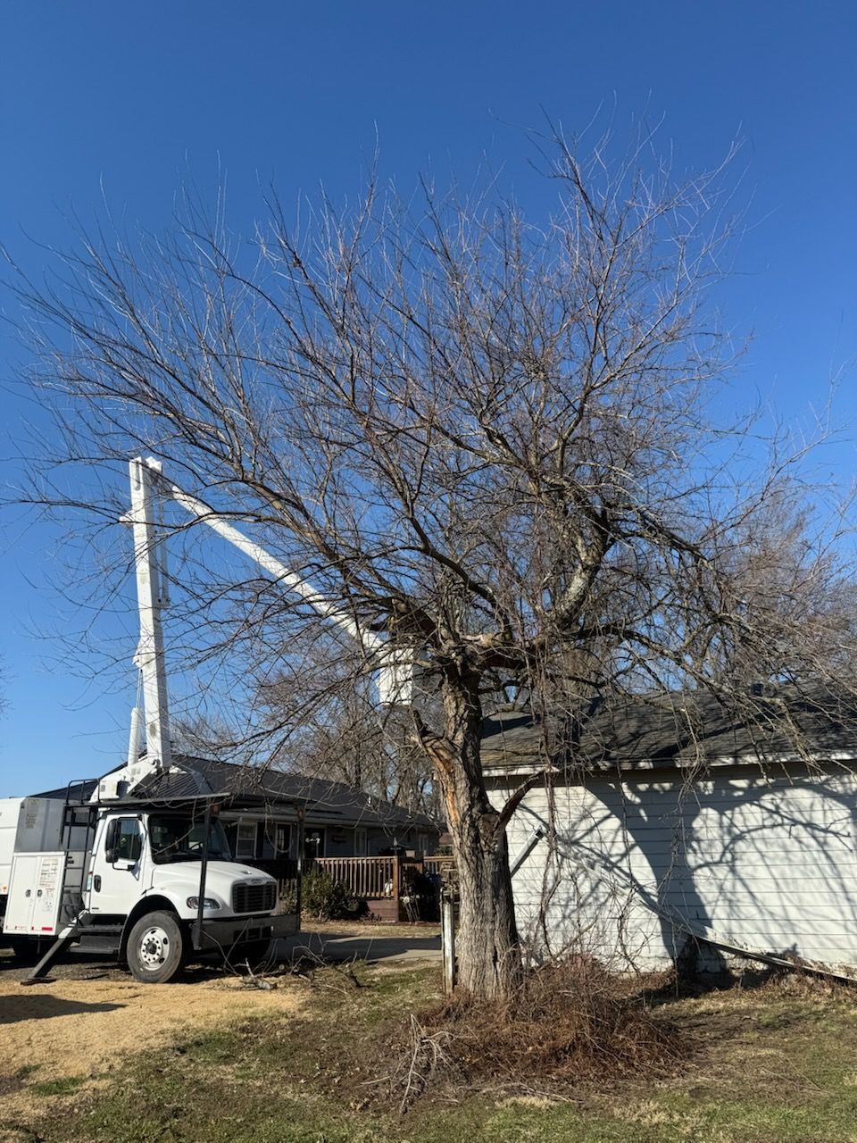 A white barn is sitting in the middle of a grassy field next to a fence.