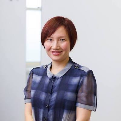 A woman in a blue plaid shirt is smiling for the camera.