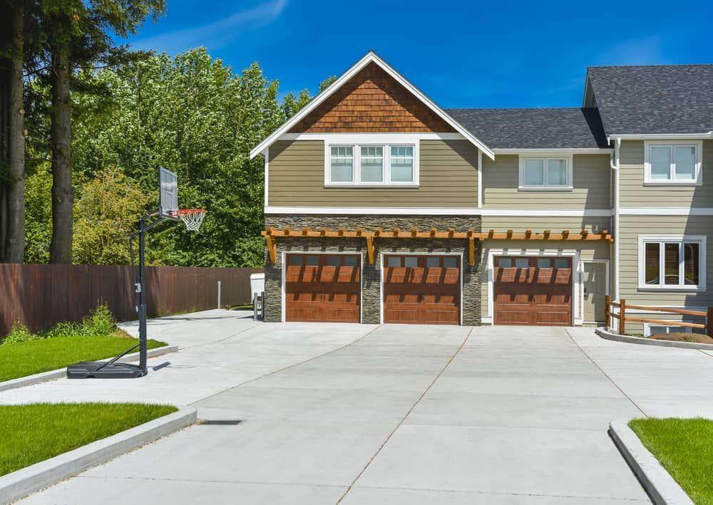 A Home With Three Wooden Garage Doors — Brett Continuous Concrete Kerbing & Edging In Lakewood, NSW