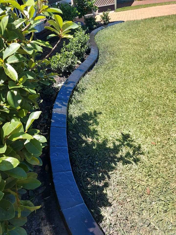 Dark Stone Edging Separates Lush Green Grass — Brett Continuous Concrete Kerbing & Edging In Lakewood, NSW
