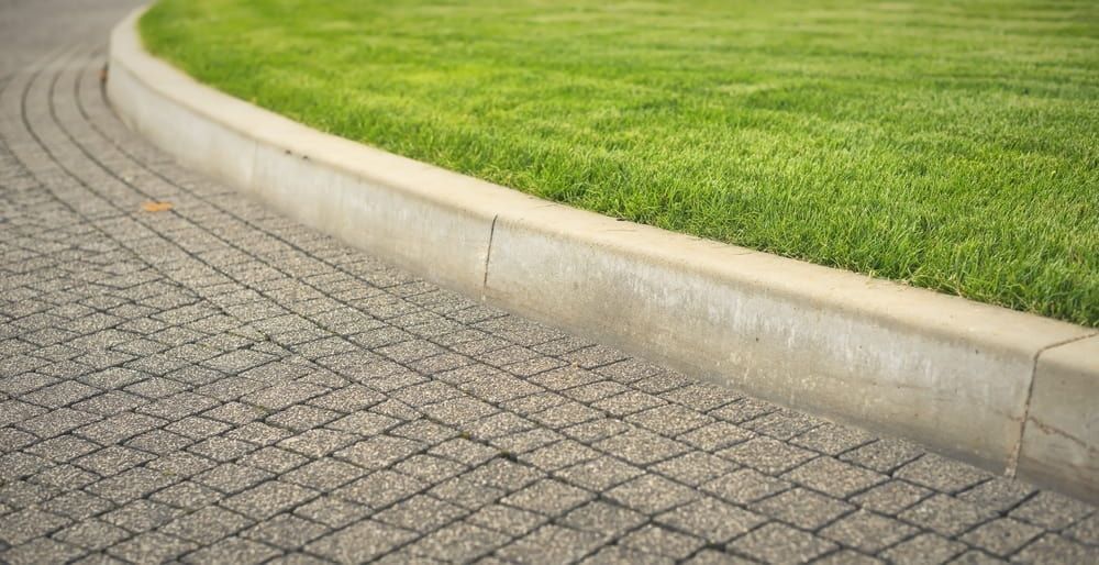 A Curved Sidewalk With Light Gray Bricks — Brett Continuous Concrete Kerbing & Edging In Lakewood, NSW