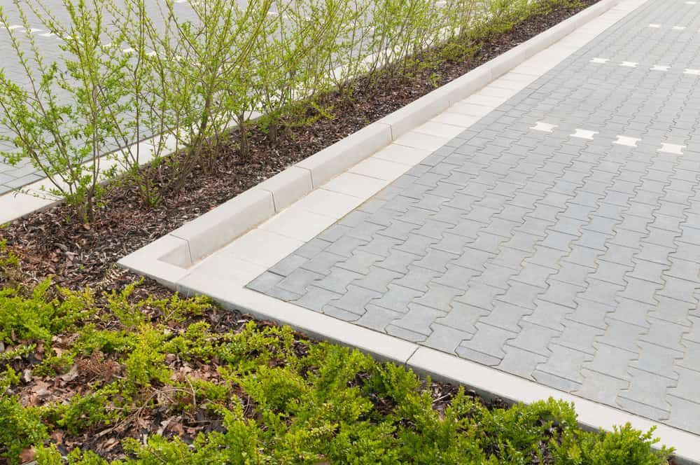A Paved Parking Space With Interlocking Grey Tiles — Brett Continuous Concrete Kerbing & Edging In Lakewood, NSW