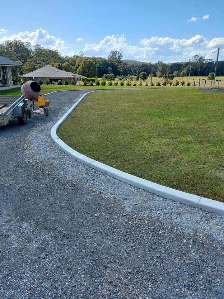 Wide Gravel Driveway Curves Bordered by White Kerbs — Brett Continuous Concrete Kerbing & Edging In Lakewood, NSW
