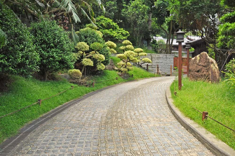 Curved Cobblestone Path Through a Lush Garden — Brett Continuous Concrete Kerbing & Edging In Lakewood, NSW