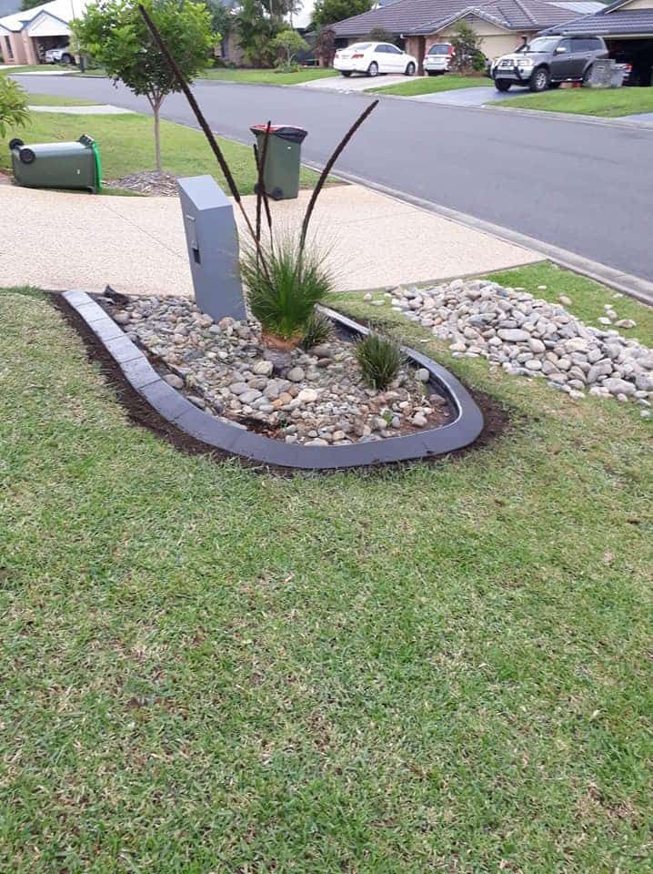 A Small Garden Bed With Pebbles and Grasses — Brett Continuous Concrete Kerbing & Edging In Wauchope, NSW
