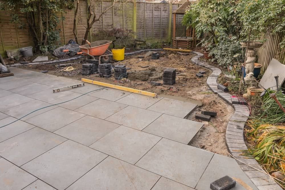 A Backyard Under Construction With a Partially Paved Stone Patio — Brett Continuous Concrete Kerbing & Edging In Bonny Hills, NSW