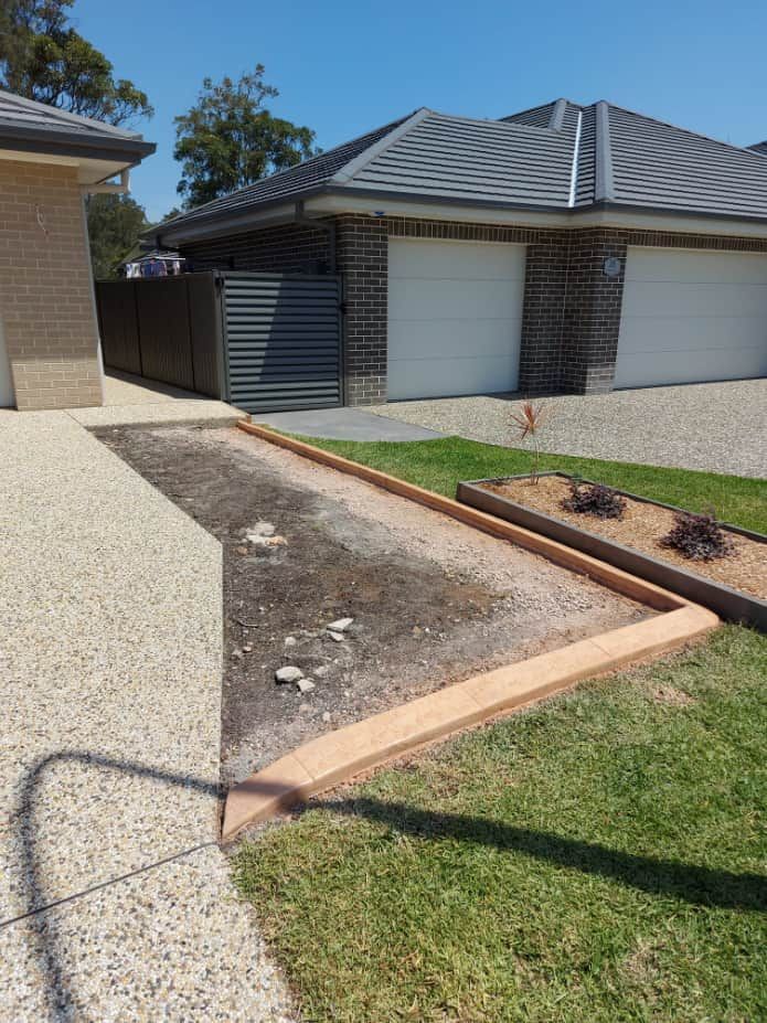 A Garden Bed Bordered by Concrete Near a Driveway — Brett Continuous Concrete Kerbing & Edging In Lakewood, NSW
