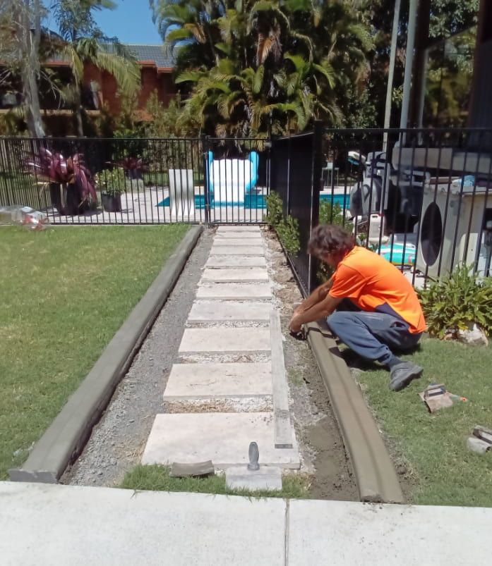 Man Installs Edging on a Stone Path — Brett Continuous Concrete Kerbing & Edging In Wauchope, NSW