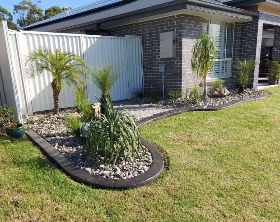 Neatly Landscaped Front Yard Bordered by a Black Edging — Brett Continuous Concrete Kerbing & Edging In Bonny Hills, NSW