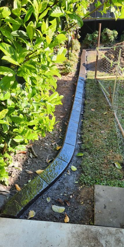 Newly Laid Concrete Garden Edging Curves Through a Backyard — Brett Continuous Concrete Kerbing & Edging In Bonny Hills, NSW