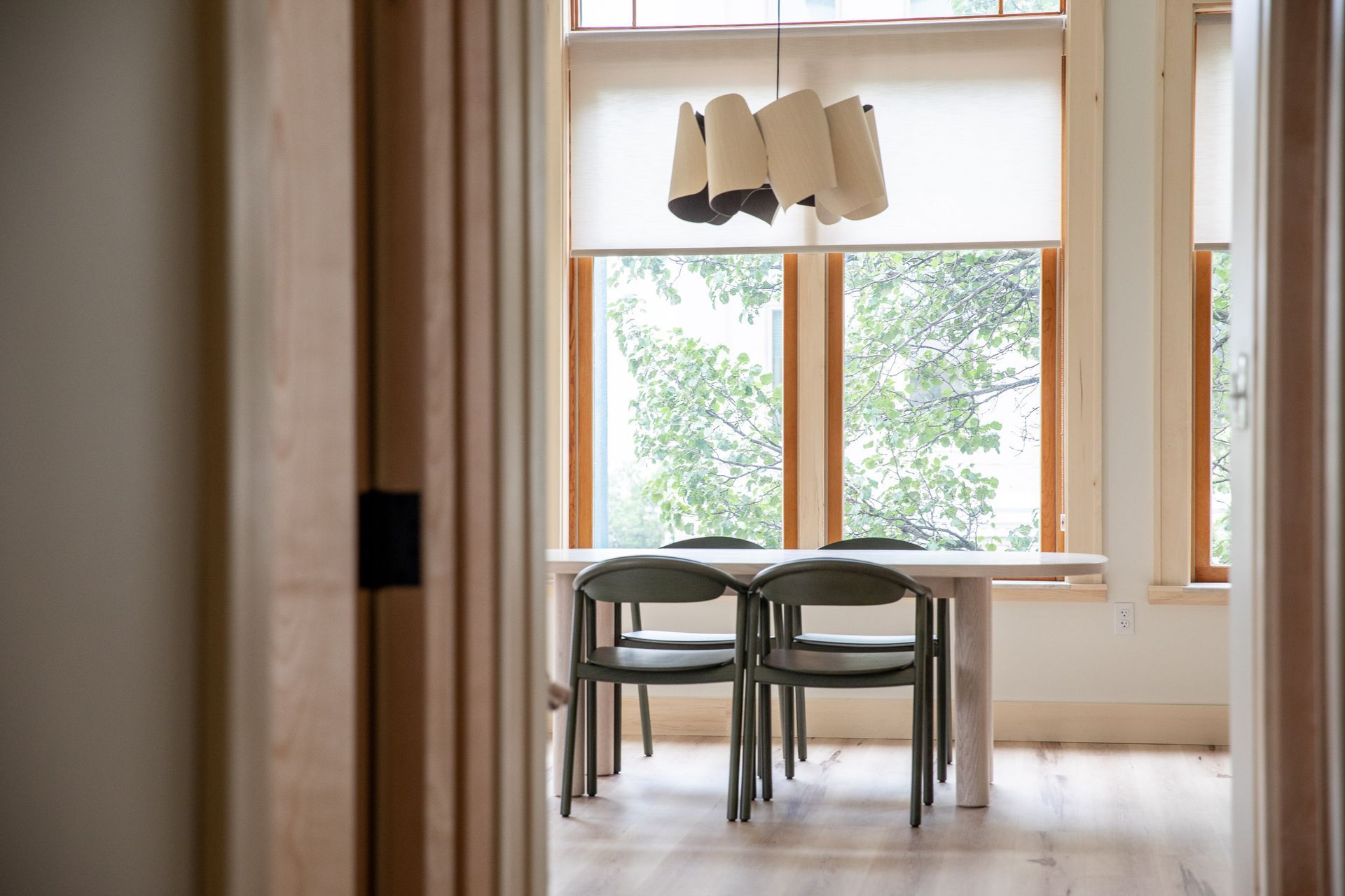 A dining room with a table and chairs in front of a window.