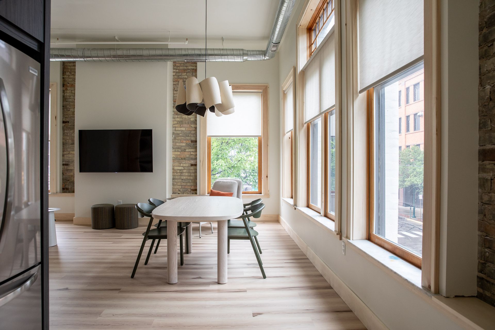 A dining room with a table and chairs and a flat screen tv on the wall.
