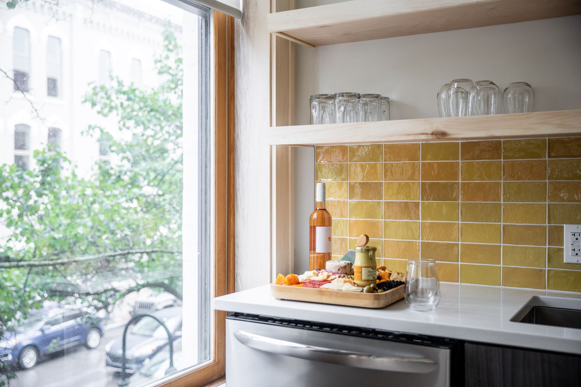 A kitchen with a bottle of wine on the counter and a window.