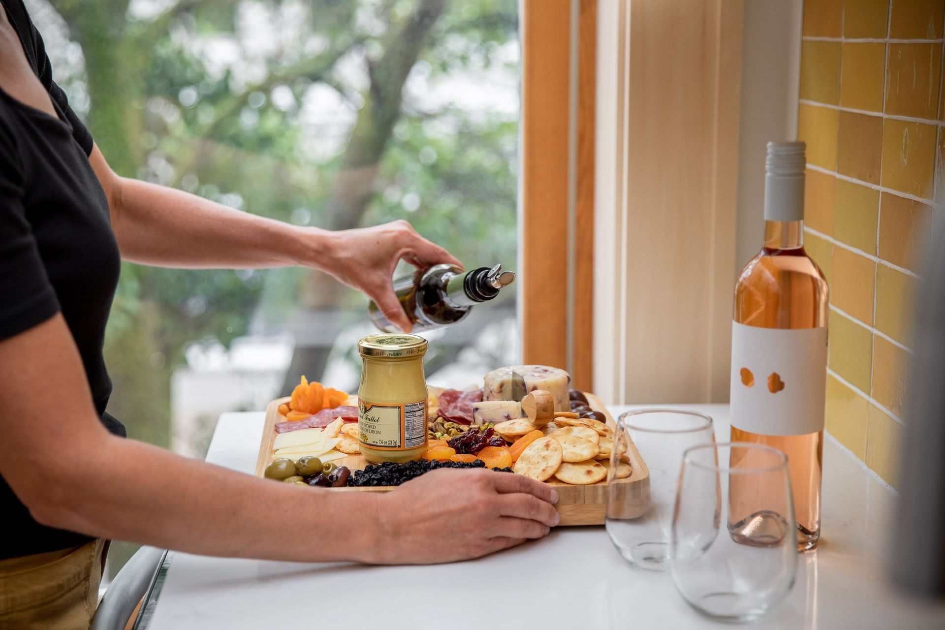 A woman is pouring wine into a jar on a cutting board.