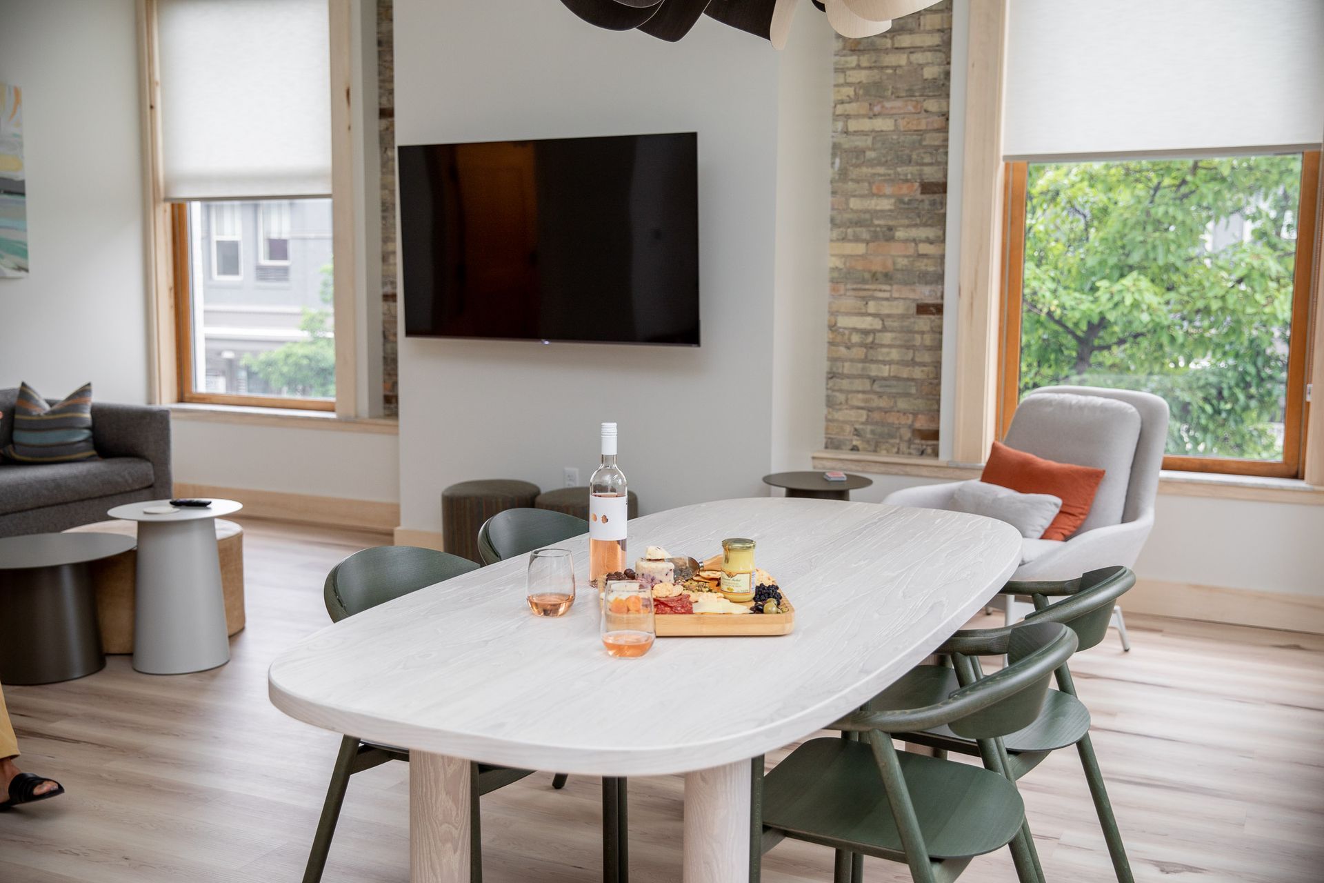 A dining room table with a bottle of wine on it and a flat screen tv on the wall.