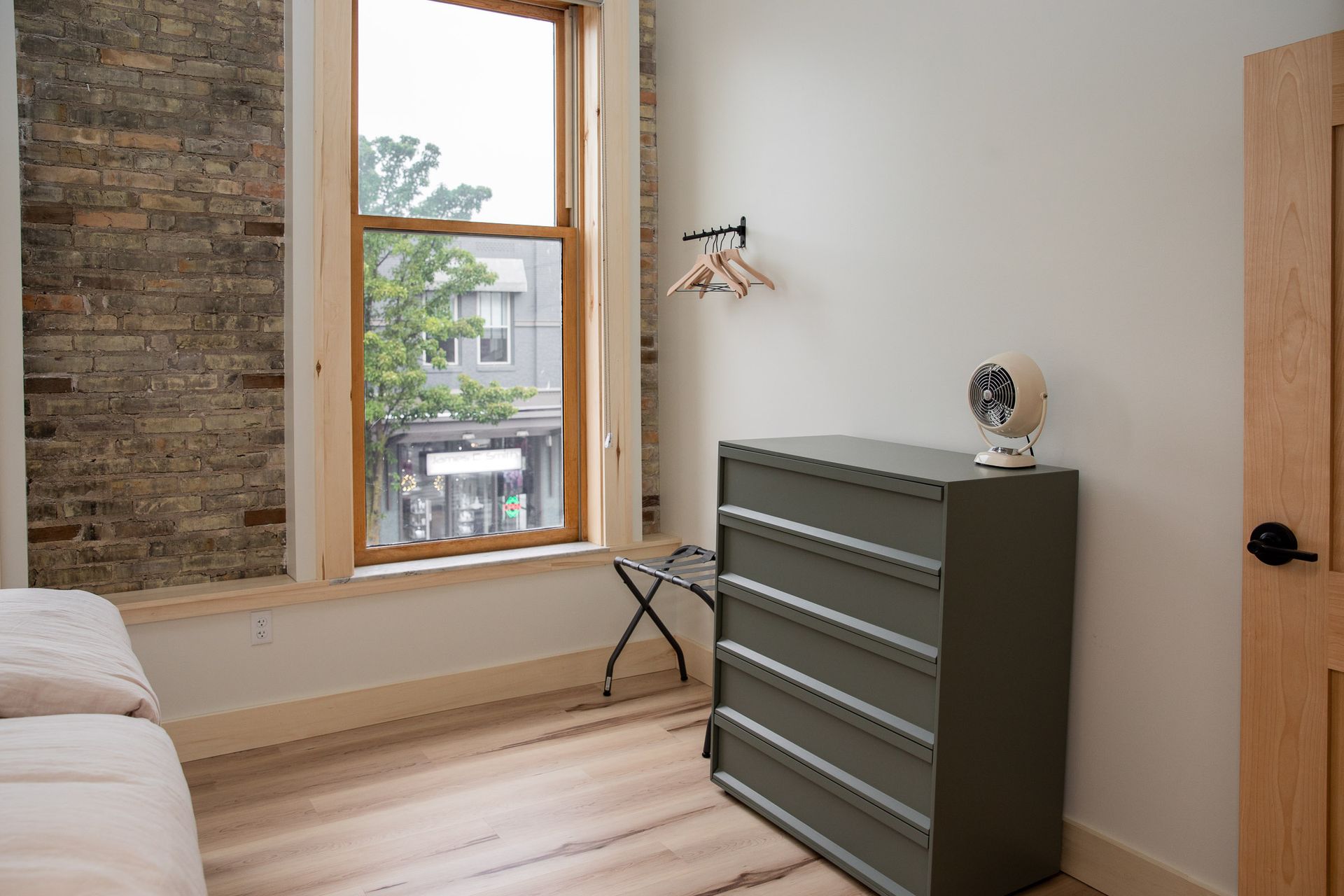 A bedroom with a bed , dresser , and window.