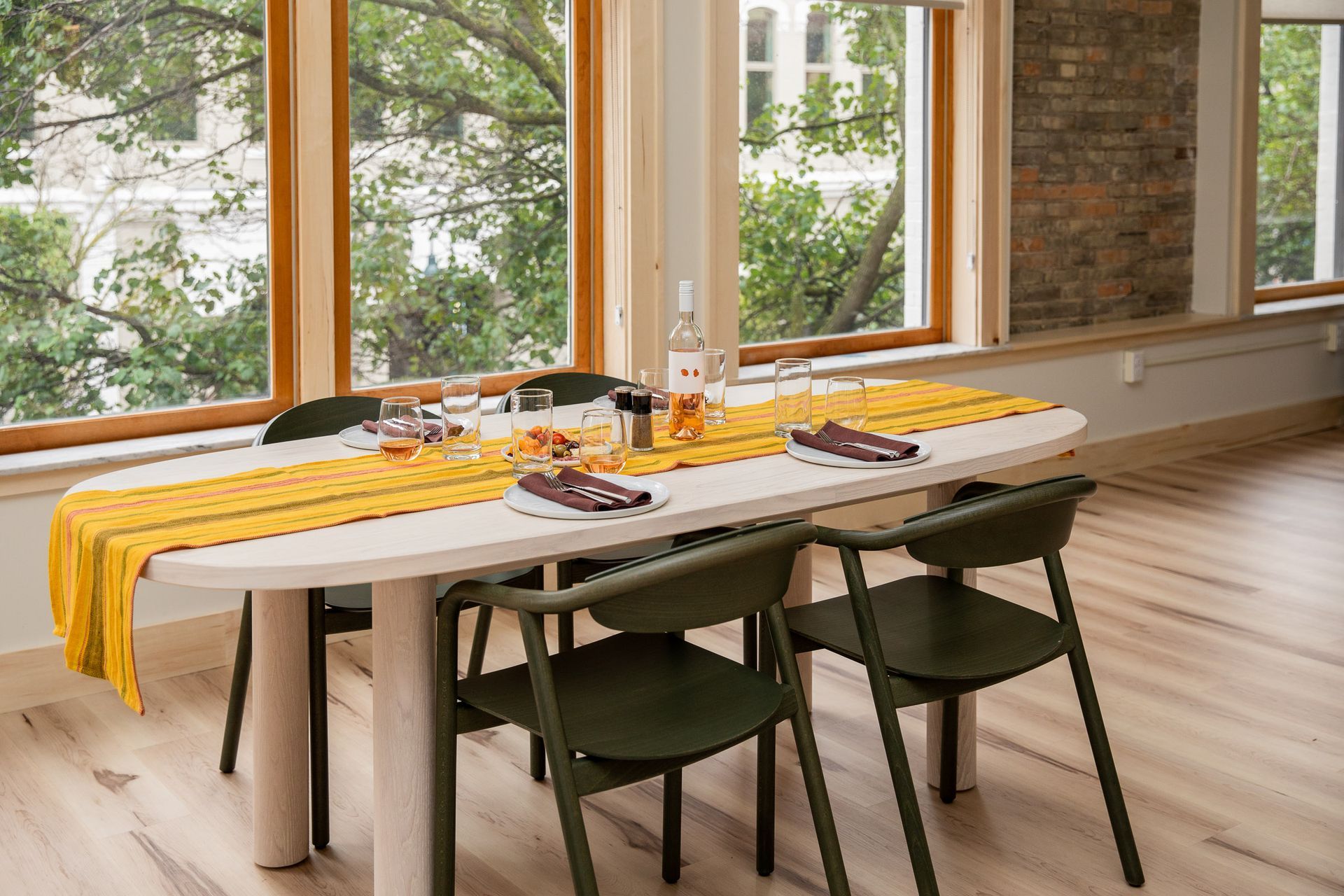 A dining room table with a yellow table runner and chairs.
