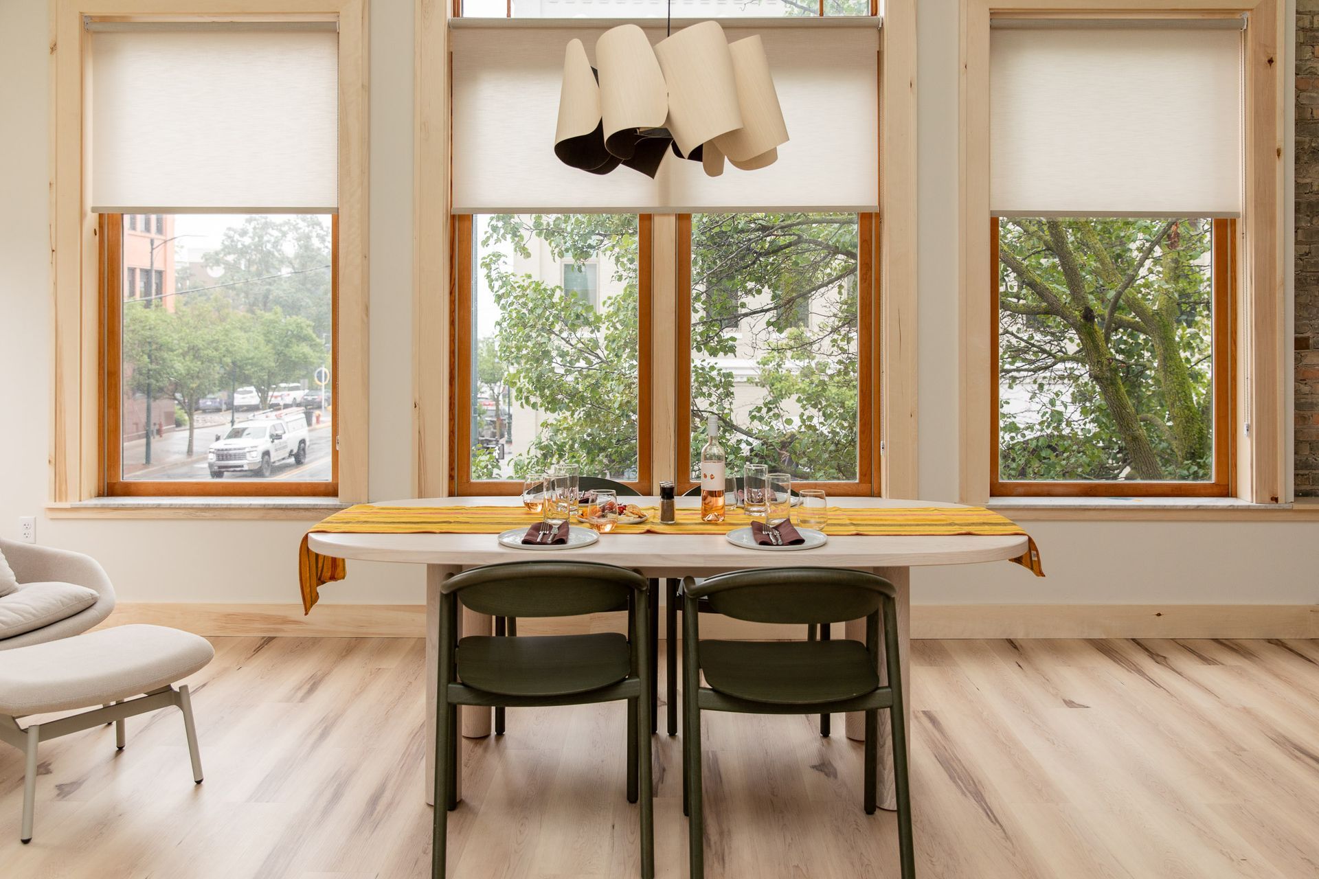 A dining room with a table and chairs and lots of windows.