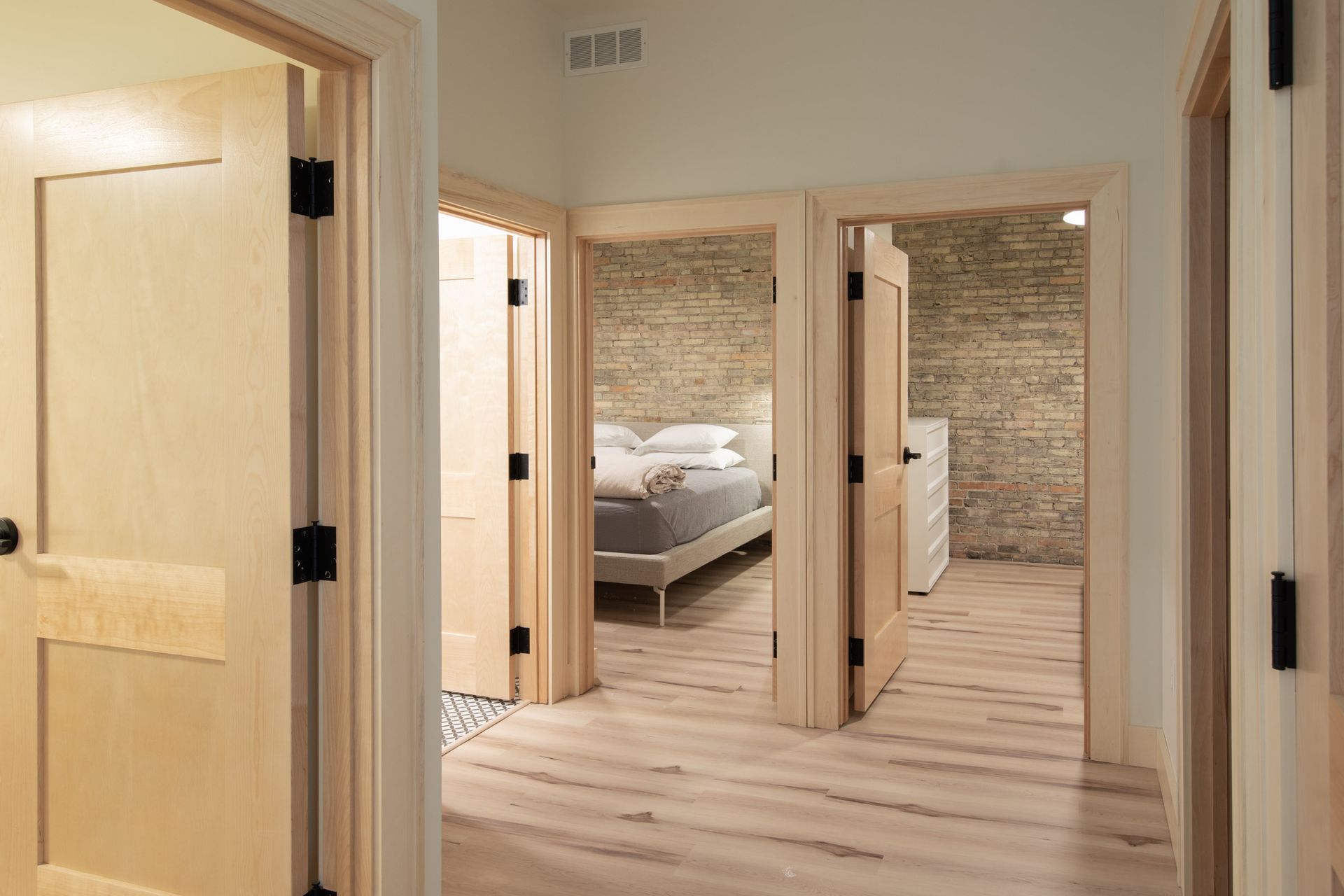 A hallway leading to a bedroom and a bathroom in a house.