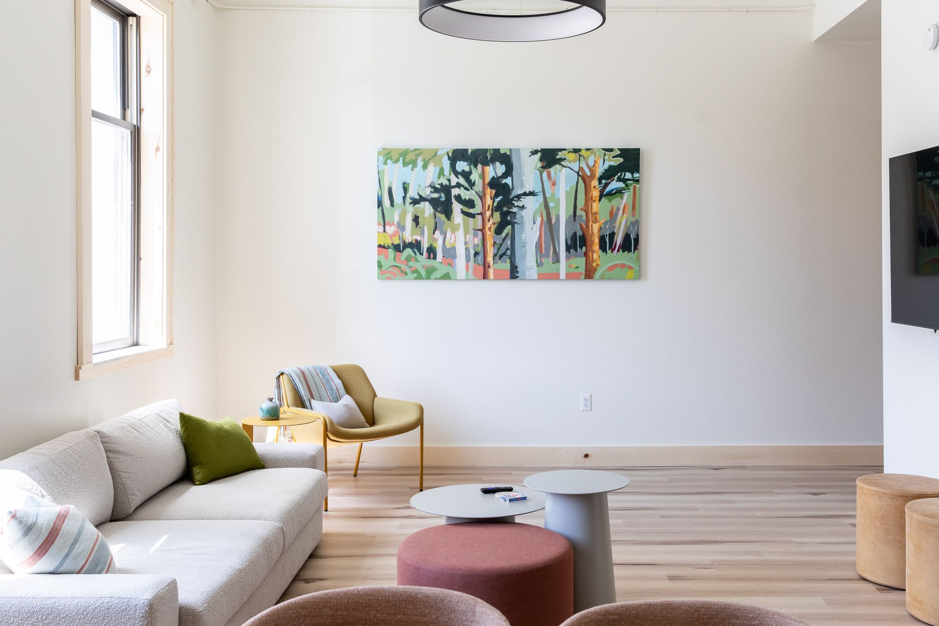 A living room with a couch , chairs , ottomans and a painting on the wall.