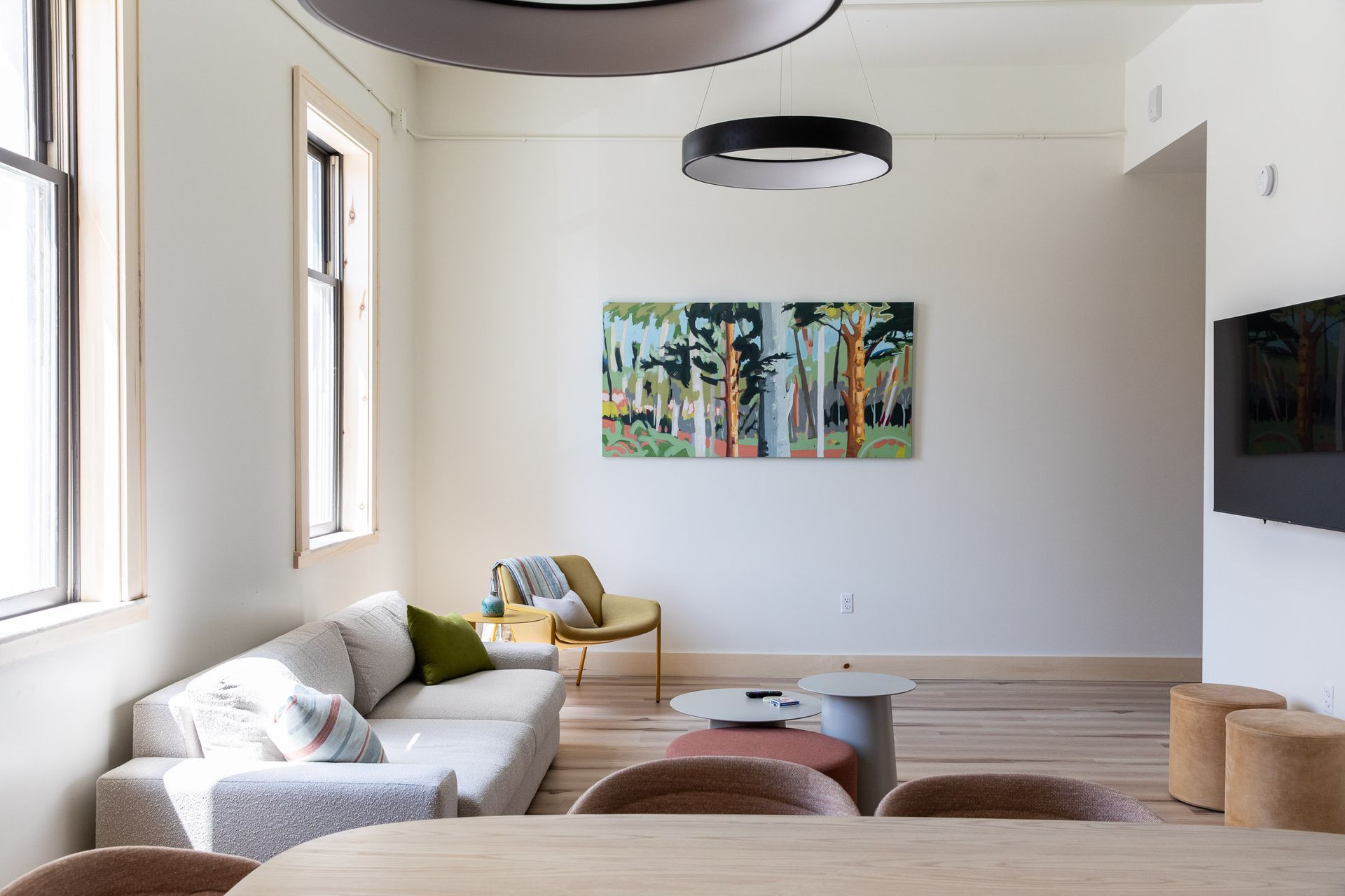 A living room with a couch , table , chairs and a painting on the wall.