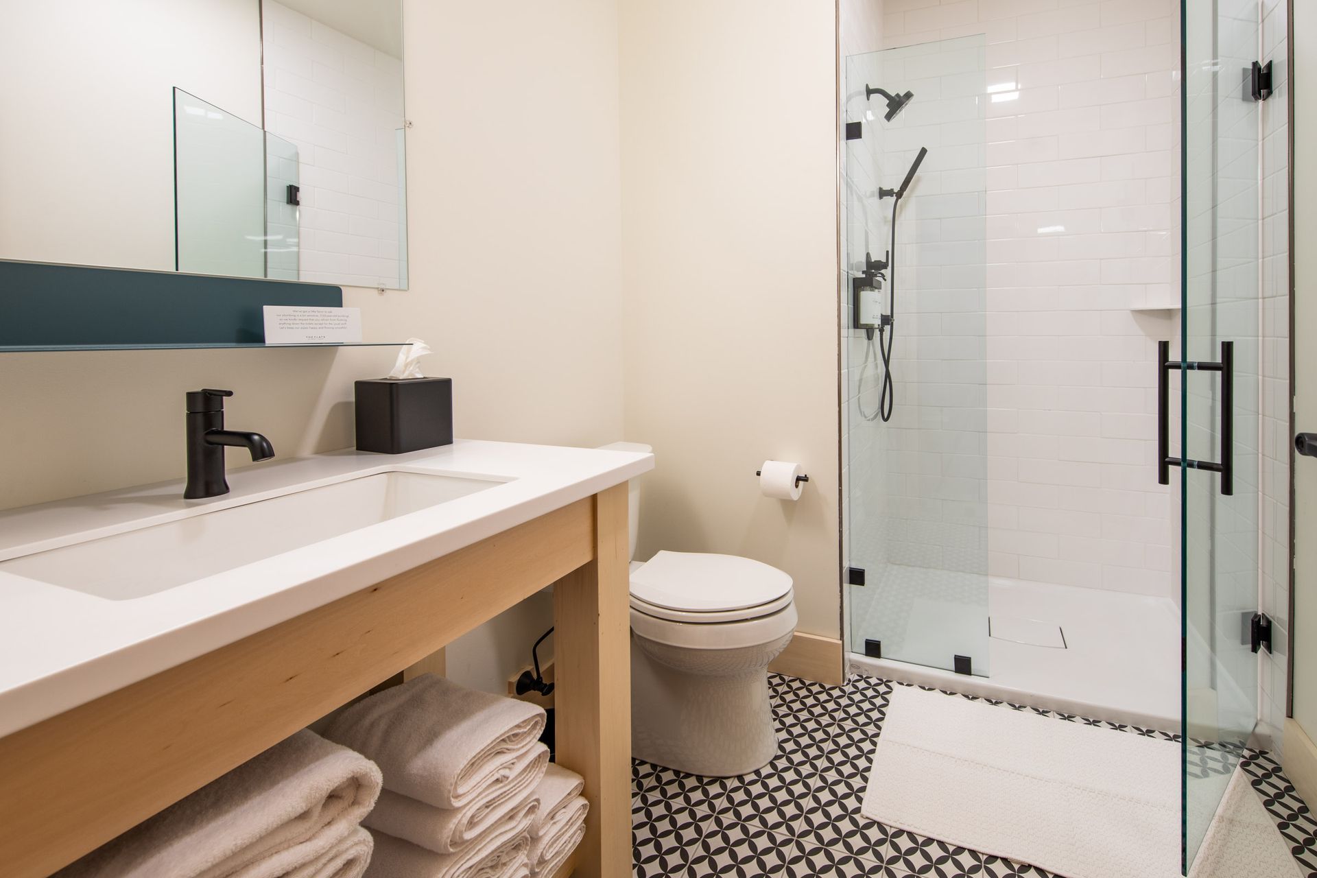 A bathroom with a toilet , sink , mirror and walk in shower.